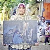 والدة «كريم» تحمل إحدى اللوحات