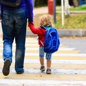 طفل صغير يرتدى «يونيفورم» المدرسة وتختفى كفه الصغيرة فى قبضة والده