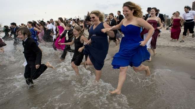 بالصور| المئات ينزلون البحر بالملابس الرسمية في مهرجان 