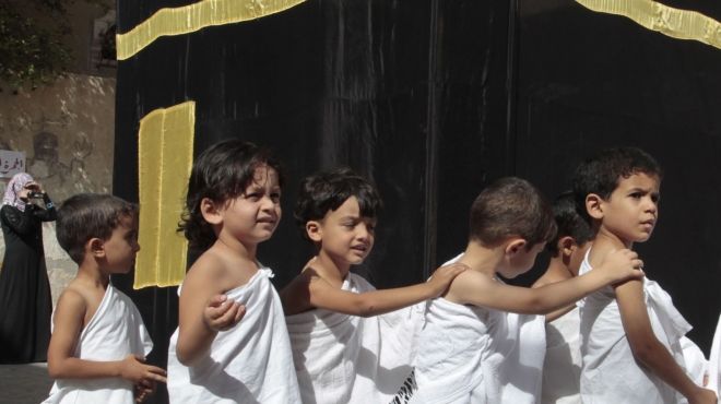  بالصور| الأطفال يرتدون ملابس الإحرام ويطوفون حول نموذج للكعبة في فلسطين 
