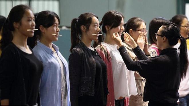  بالصور| الصين تُعلم الشباب الابتسام باستخدام عصا الطعام 