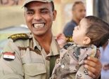  صورة اليوم| ضابط بالجيش يحمل طفل رضيع يرتدي بدلة عسكرية بـ